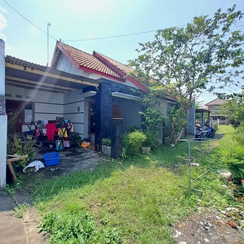 Dari Foto ini, tanpa merubah bentuk, tanpa merubah angle foto, tanpa merubah posisi rumah, tanpa merubah dimensi, tanpa merubah dan mengurangi detail rumah. Tanpa merubah jalan depan rumah. Buat foto ini menjadi lebih detail, lebih realistis, dan lebih jernih 8K. Tambahkan brightness dan Contrast yang seimbang pada foto bagian depan rumah. Tambahkan pencahayaan cinematic dari berbagai sisi. Kurangi shadow pada detail rumah sehingga lebih terlihat jelas. Hilangkan mobil, hilangkan sepeda moto, dah hilangkan sampah pada depan rumah. Hilangkan Spanduk. Jangan rubah jalan depan rumah. Buat langit menjadi biru cerah dan sedikit awan. Buat kondisi menjadi siang hari yang cerah. Rubah ukuran dimensi foto menjadi portrait 4:5. Komposisikan menambah luas langit nya. Zoom out foto ini agar rumah menjadi lebih kecil, dan sudut pandang menjadi lebih jelas. Jangan rubah bentuk jalan depan rumah. Terangkan bagian depan rumah yang masih gelap.