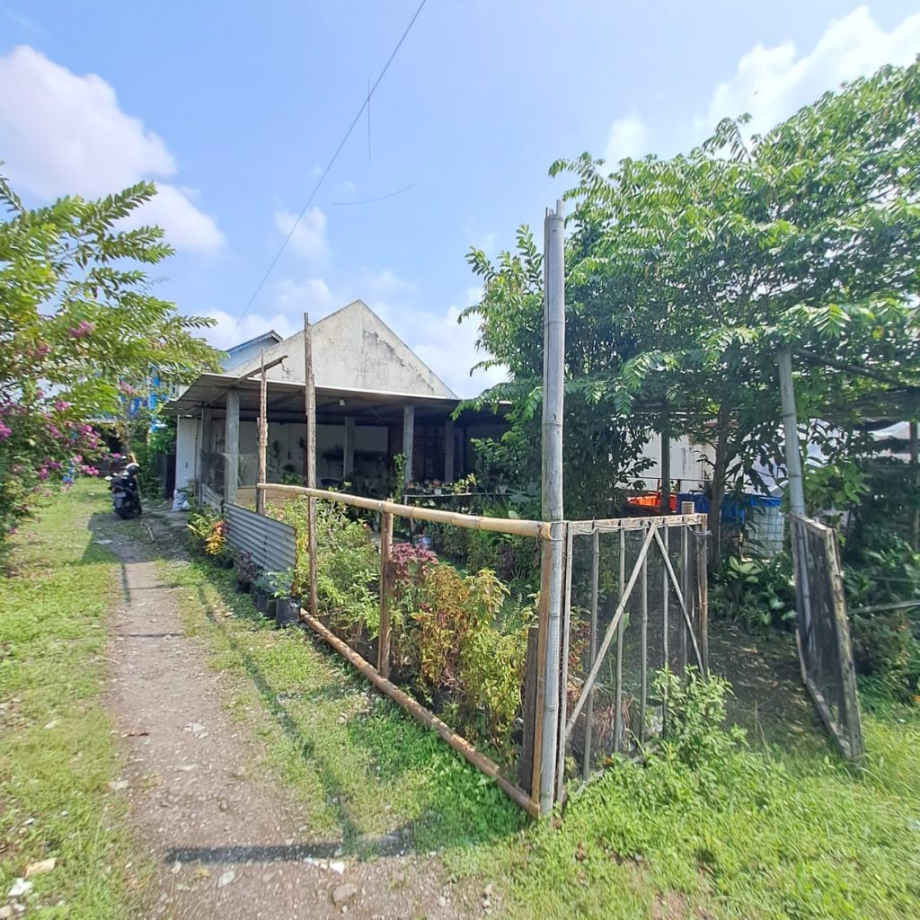 Dari Foto ini, tanpa merubah bentuk, tanpa merubah angle foto, tanpa merubah posisi rumah, tanpa merubah dimensi, tanpa merubah dan mengurangi detail rumah. Tanpa merubah jalan depan rumah. Buat foto ini menjadi lebih detail, lebih realistis, dan lebih jernih 8K. Tambahkan brightness dan Contrast yang seimbang pada foto bagian depan rumah. Tambahkan pencahayaan cinematic dari berbagai sisi. Kurangi shadow pada detail rumah sehingga lebih terlihat jelas. Hilangkan mobil, hilangkan sepeda moto, dah hilangkan sampah pada depan rumah. Hilangkan Spanduk. Jangan rubah jalan depan rumah. Buat langit menjadi biru cerah dan sedikit awan. Buat kondisi menjadi siang hari yang cerah. Rubah ukuran dimensi foto menjadi portrait 4:5. Komposisikan menambah luas langit nya. Zoom out foto ini agar rumah menjadi lebih kecil, dan sudut pandang menjadi lebih jelas. Jangan rubah bentuk jalan depan rumah. Terangkan bagian depan rumah yang masih gelap.