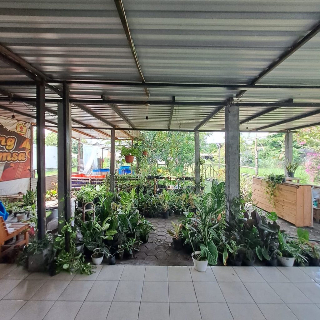 Dari Foto ini, tanpa merubah bentuk, tanpa merubah angle foto, tanpa merubah posisi rumah, tanpa merubah dimensi, tanpa merubah dan mengurangi detail rumah. Tanpa merubah jalan depan rumah. Buat foto ini menjadi lebih detail, lebih realistis, dan lebih jernih 8K. Tambahkan brightness dan Contrast yang seimbang pada foto bagian depan rumah. Tambahkan pencahayaan cinematic dari berbagai sisi. Kurangi shadow pada detail rumah sehingga lebih terlihat jelas. Hilangkan mobil, hilangkan sepeda moto, dah hilangkan sampah pada depan rumah. Hilangkan Spanduk. Jangan rubah jalan depan rumah. Buat langit menjadi biru cerah dan sedikit awan. Buat kondisi menjadi siang hari yang cerah. Rubah ukuran dimensi foto menjadi portrait 4:5. Komposisikan menambah luas langit nya. Zoom out foto ini agar rumah menjadi lebih kecil, dan sudut pandang menjadi lebih jelas. Jangan rubah bentuk jalan depan rumah. Terangkan bagian depan rumah yang masih gelap.